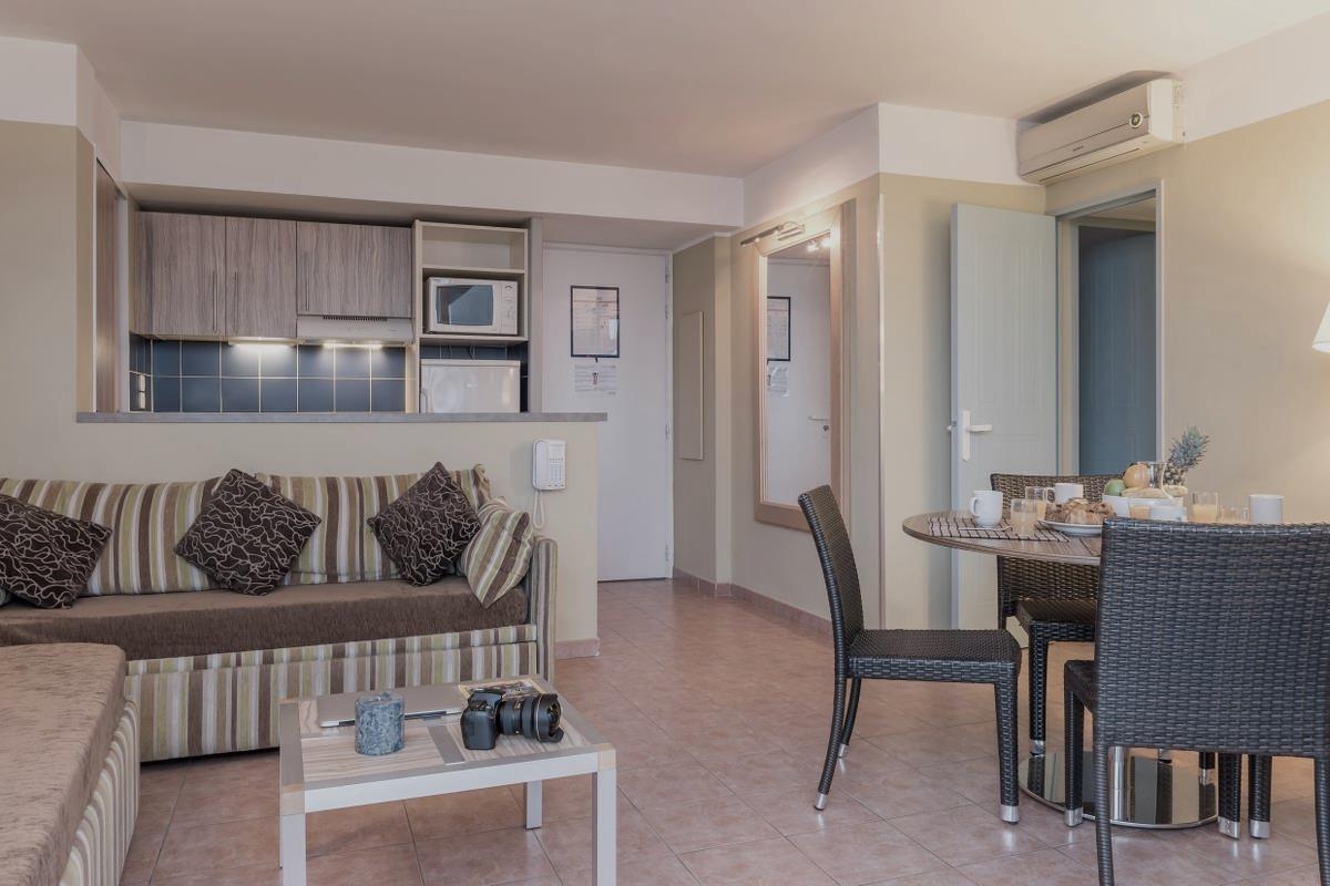 Moderne stue med stripete sofa, spisebordssett, kamera på salongbordet og utsikt til et lite kjøkkenområde.